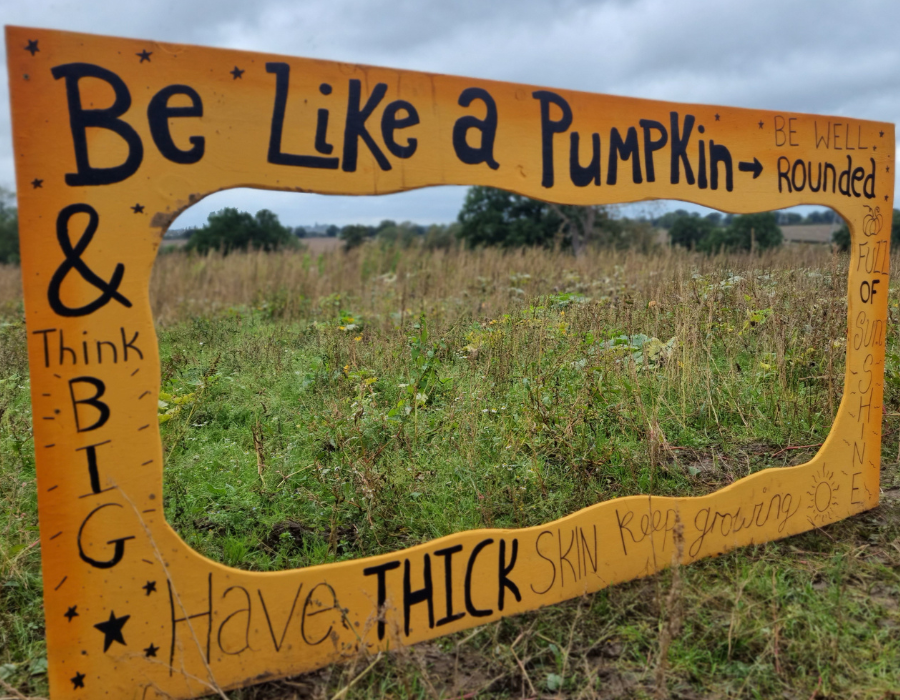 Giant Frame in orange colour with funky written text Be Like a Pumpkin, well rounded and think big in the middle of the grass field set us as a selfie prompt during halloween event in derby