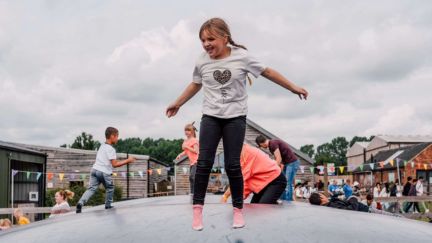 young girl with two plats jumping and smiling on a giant inflatable bouncy pillow 