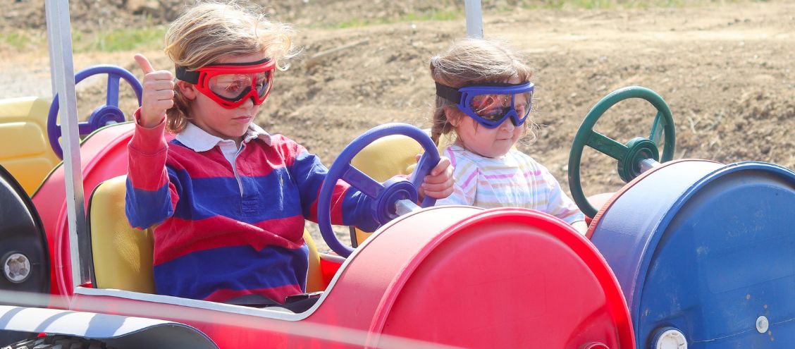 Children wearing colourful goggles enjoying the MooFest barrel ride at Bluebell Dairy Farm in Derbyshire
